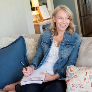 Laurie Hise smiling on a couch while writing in a planner